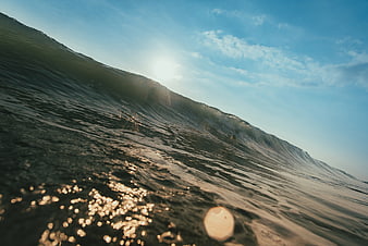 Dramatic Ocean Wave Crest With Sun Flare And Sparkling Water Surface