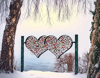 Two heart-shaped love lock fences in a snowy winter landscape