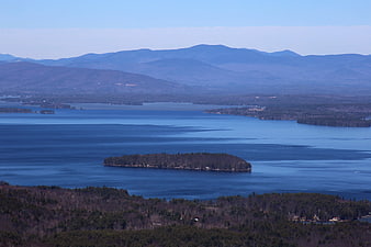 Aerial View of Brown Island in Blue Lake with Mountains