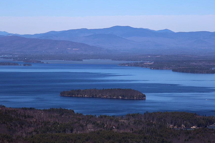 Aerial View of Brown Island in Blue Lake with Mountains