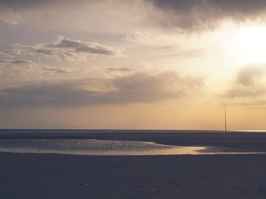 Serene Beach Sunset with Sunbeams and Clouds