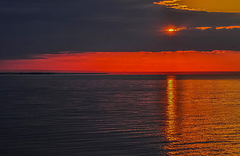 Vibrant Orange Sunset Over Calm Ocean with Clouds