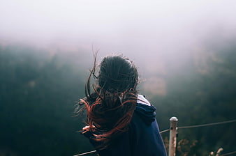 Woman with Windblown Hair Looking at Foggy Mountain View