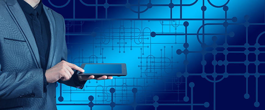 Businessman using tablet against blue circuit board technology background