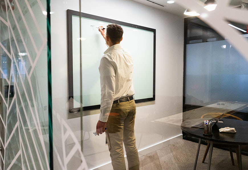 Businessman writing on whiteboard in modern office