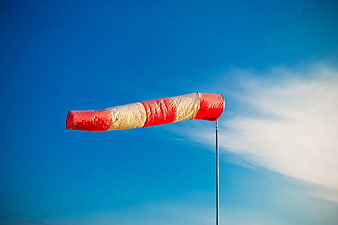 Red and white windsock fluttering against a clear blue sky