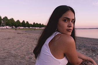 Young Woman Sitting on Beach at Sunset Looking Back