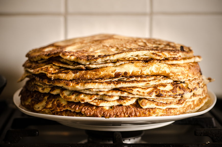 Stack of golden homemade pancakes on white plate