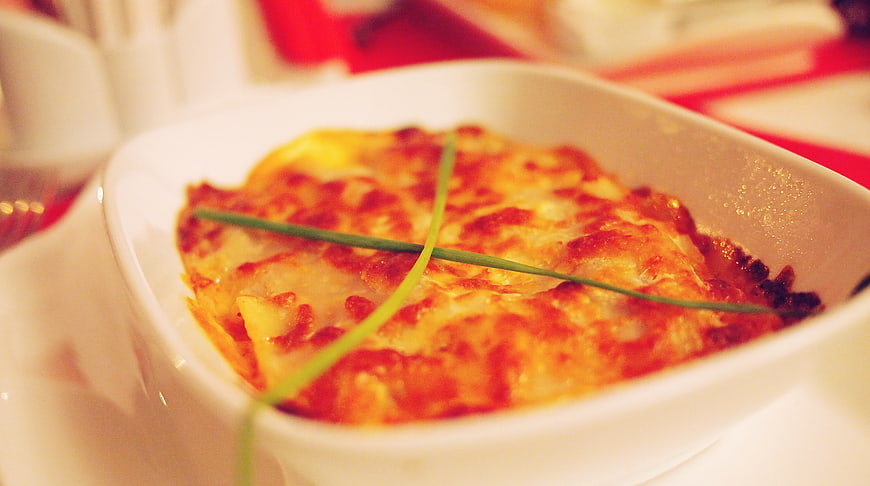 Close-up of baked lasagna with melted cheese and chives