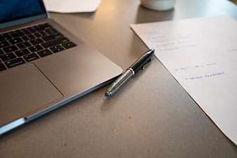 Laptop, pen, and handwritten notes on a desk