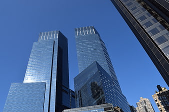 Low angle view of modern glass skyscrapers against blue sky