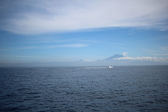 Speedboat crossing blue sea with distant mountain landscape