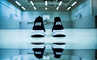 Black Nike sneakers on basketball court floor