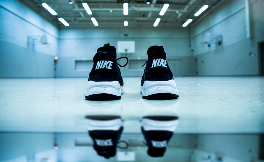 Black Nike sneakers on basketball court floor