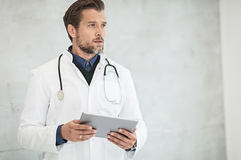 Male Doctor Holding Tablet with Stethoscope Around Neck
