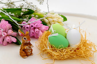 Easter bunny figurine with pastel eggs in straw nest and pink hyacinths