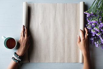 Flat lay of hands holding blank paper with coffee and purple flowers
