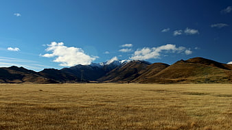 Golden Highland Meadow with Snow-Capped Mountains and Blue Sky