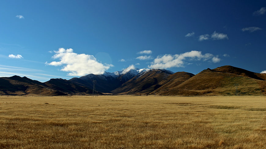 Golden Highland Meadow with Snow-Capped Mountains and Blue Sky