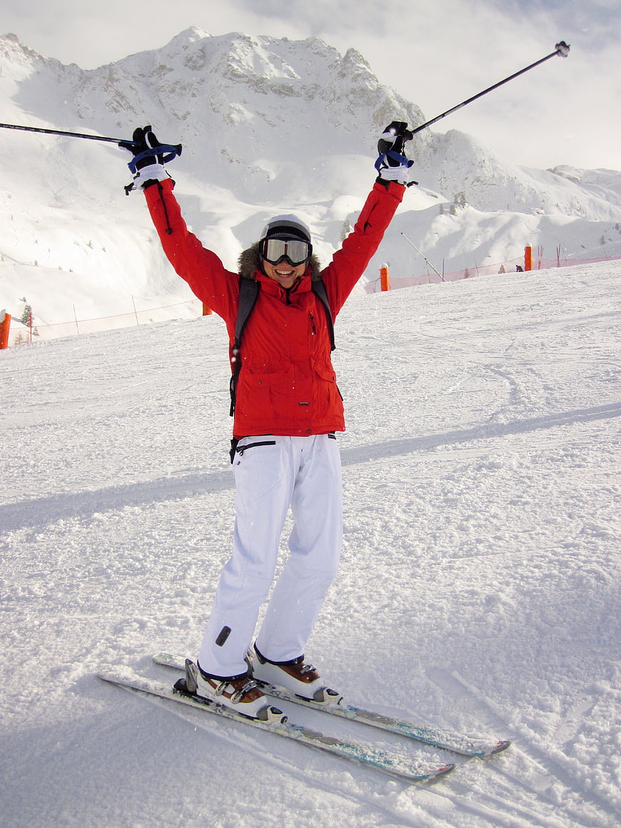 Happy Woman Skiing with Arms Raised on Snowy Mountain Slope