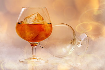 Brandy Glass With Ice And Smoke Against Warm Bokeh Background