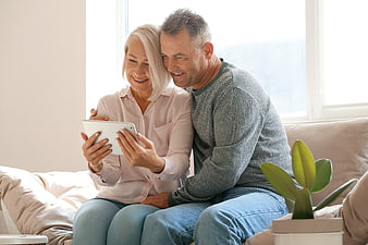 Happy senior couple using tablet on sofa at home