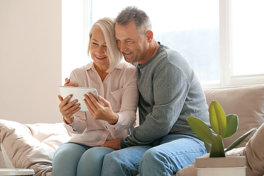 Happy senior couple using tablet on sofa at home