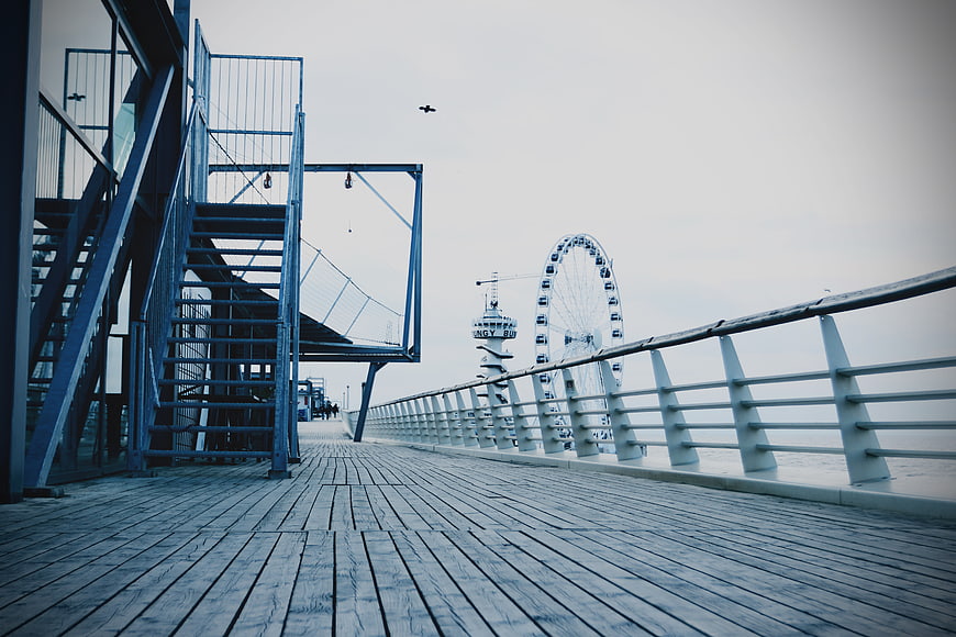 Empty wooden pier with Ferris wheel and blue staircase