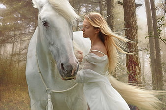 Ethereal woman in white dress embracing white horse in misty forest