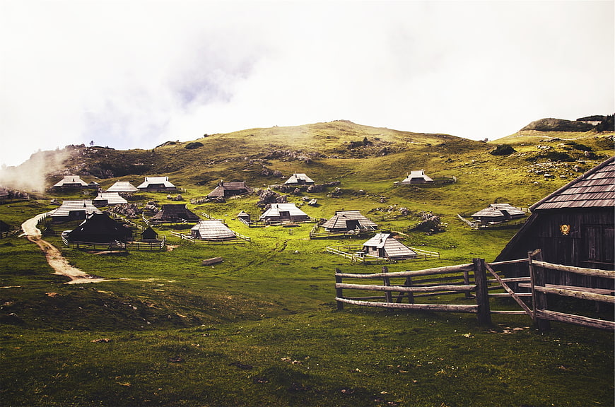 Rustic mountain village with wooden huts and green pastures