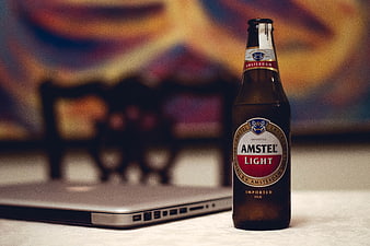 Amstel Light beer bottle next to laptop on table