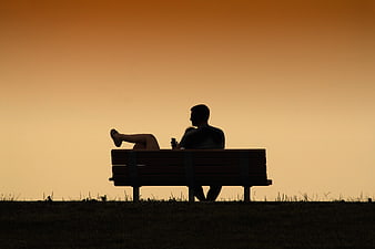 Silhouette of couple relaxing on park bench at sunset