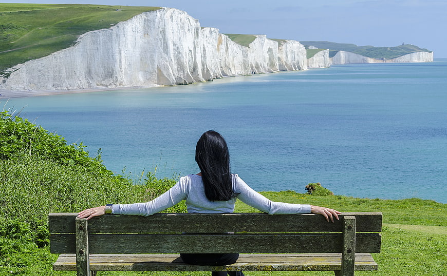Woman Relaxing on Bench Overlooking White Cliffs of Dover