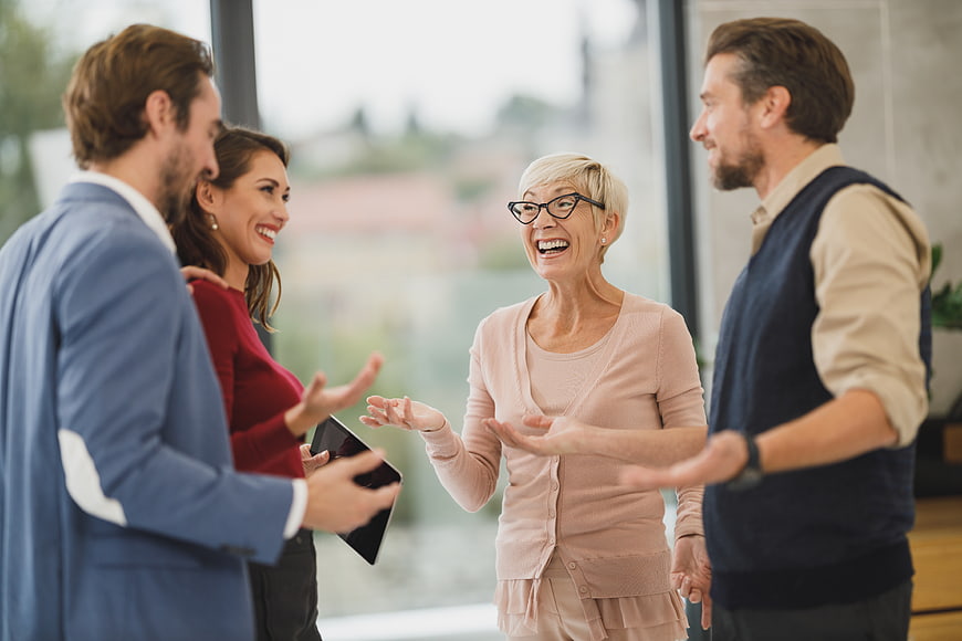 Happy senior woman laughing with colleagues in office