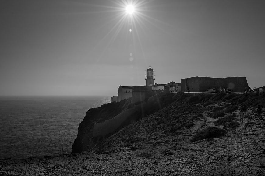 Black and white lighthouse on rocky coastal cliff