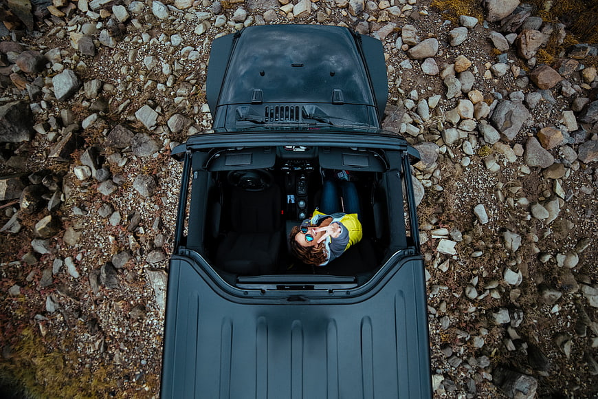 Aerial view of woman in yellow jacket driving black jeep off-road