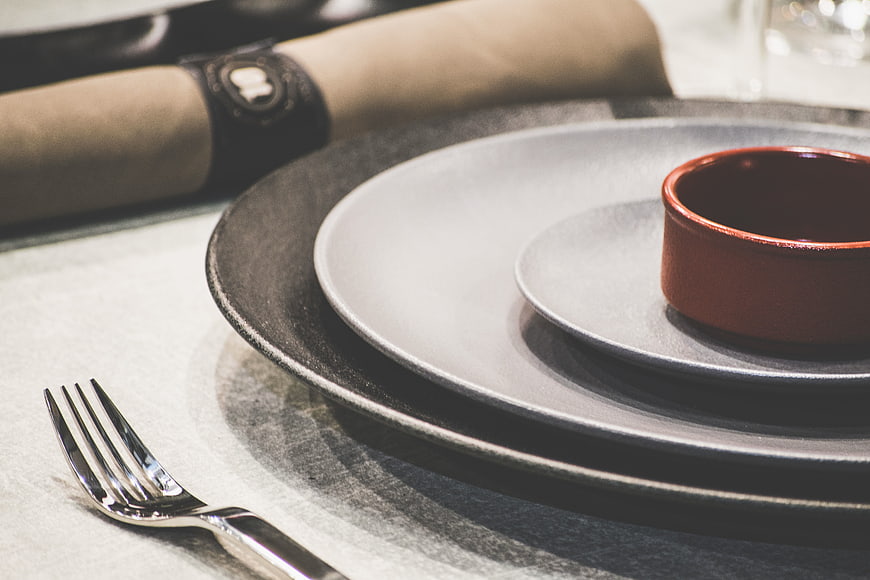 Elegant dark table setting with red bowl and silver fork