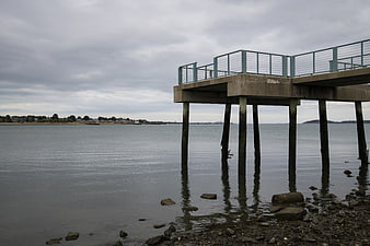 Concrete pier structure over calm water on cloudy day