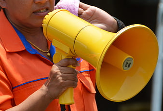 Person in Orange Vest Holding Yellow Megaphone