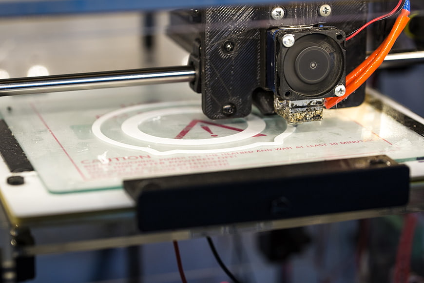 Close-up of 3D printer extruder head printing white filament