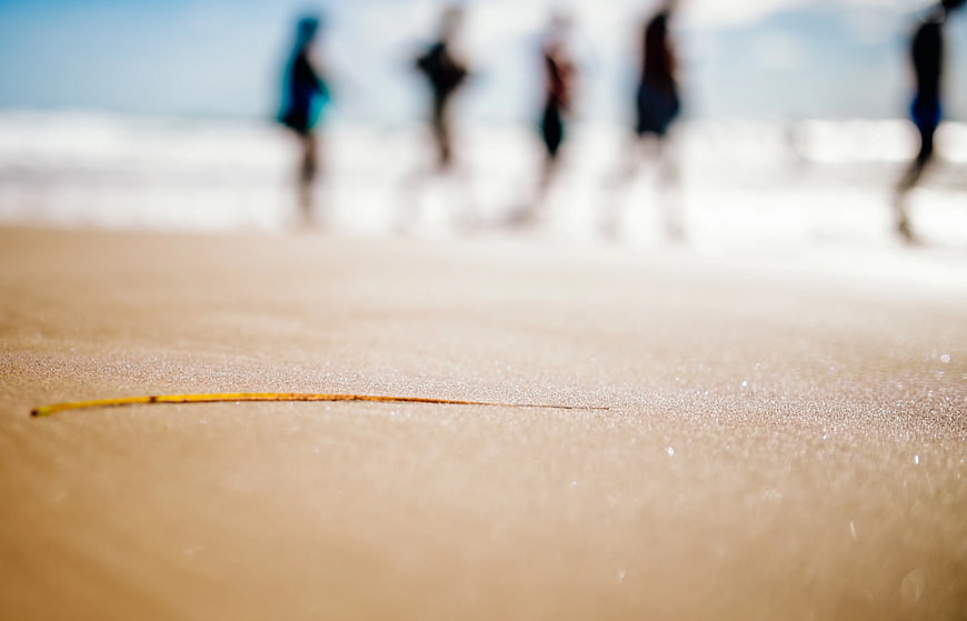 Close-up of Sand Texture with Blurred People on Beach