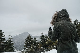 Person in Winter Parka Looking at Snowy Mountain Landscape
