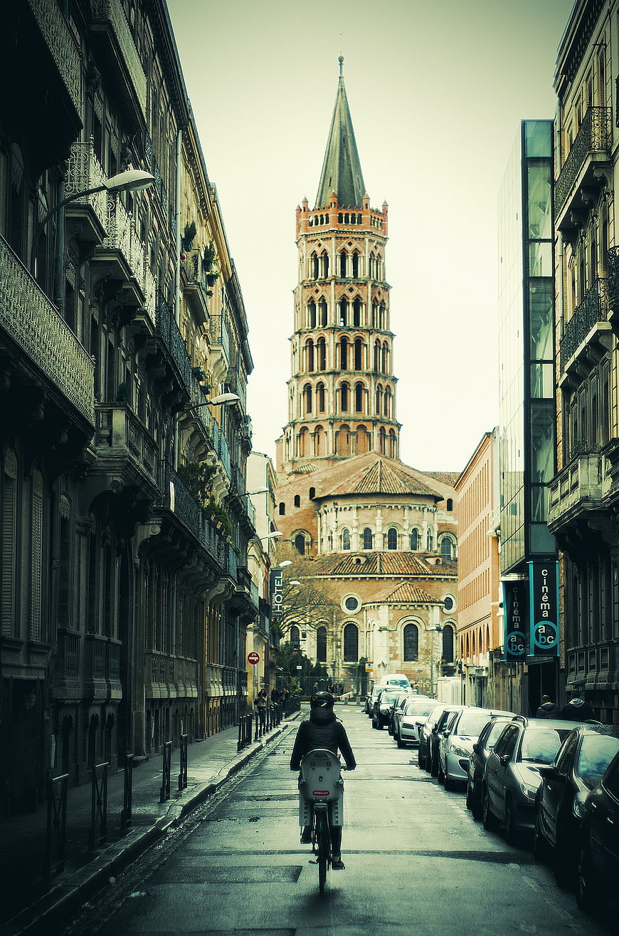 Cyclist riding down street towards historic Italian church tower