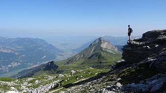 Hiker standing on rocky mountain peak overlooking vast valley