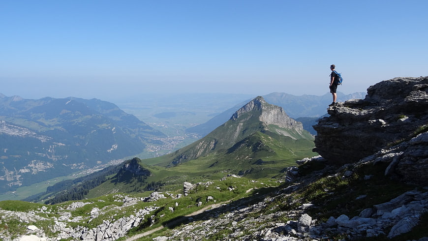Hiker standing on rocky mountain peak overlooking vast valley