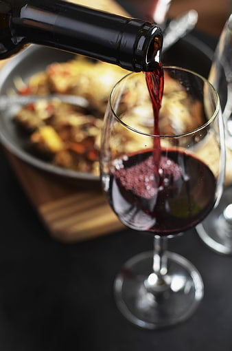 Pouring Red Wine into Glass with Dinner Background