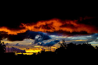 Dramatic sunset with fiery orange clouds over silhouette
