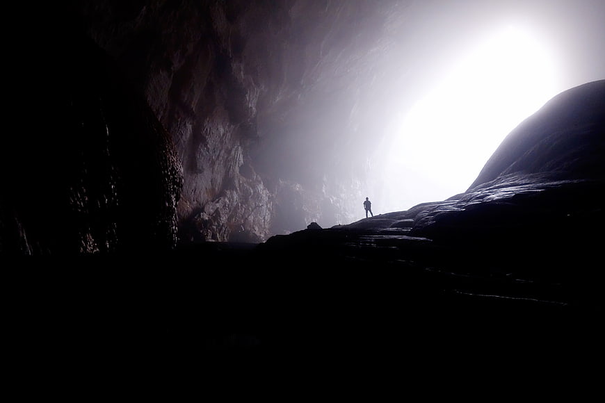 Silhouette of Man Standing in Dark Cave Entrance
