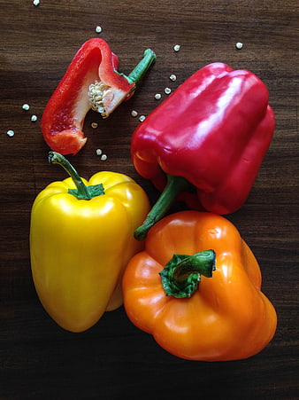 Fresh Red, Yellow, and Orange Bell Peppers on Dark Wood
