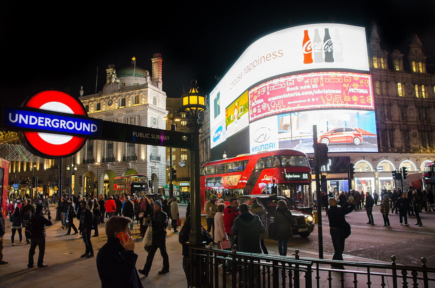 Night view of Piccadilly Circus London with red bus and underground sign